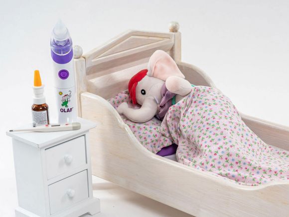 OLAF® neben Miniaturbettchen mit 'krankem' Stoffelefant